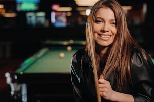 A girl with a cue in her hands is standing in a billiard club.Russian billiards photo