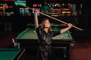 A girl with a cue in her hands is standing in a billiard club.Russian billiards photo