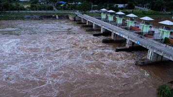 La vista aérea del agua liberada del canal de drenaje de la presa de hormigón es una forma de desbordamiento de agua en la temporada de lluvias. vista superior de los flujos de agua turbia del bosque marrón de una presa en tailandia. foto