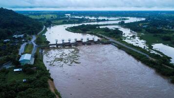 Aerial view of water released from the drainage channel of the concrete dam is a way of overflowing water in the rainy season. Top view of turbid brown forest water flows from a dam in Thailand. photo