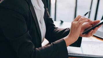 A woman playing a mobile phone by the window, a young businesswoman and a young executive founded a startup that has consistently made high profits. Concept of young businesswoman and startup company. video