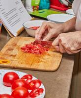 del chef manos corte Fresco Tomates en de madera corte tablero en cocina foto