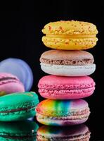 Assorted colorful macarons folded and arranged on a black surface with reflection photo