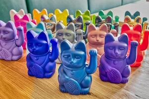 Collection of Japanese maneki cats of various colors on wooden tableGenerated image photo