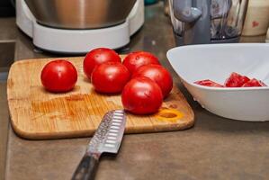 del chef manos corte Fresco Tomates en de madera corte tablero en cocina foto