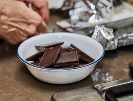 Chef Cooking Chocolate Mousse in Home Kitchen with Saucepan and Spoon photo