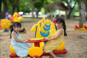 Children sit on a carousel in the playground together. Children playing at outdoor playground in the park on summer vacation. Healthy activity. photo