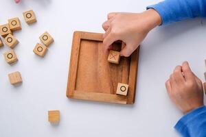 hermanos pequeños jugando al juego de mesa de madera tic-tac-toe en la mesa en la sala de estar. familia pasando tiempo juntos el fin de semana. foto