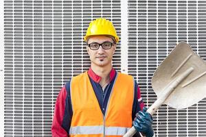 portrait of a young engineer wearing a helmet against metal background photo