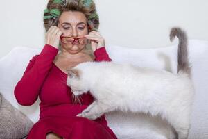 beautiful lady with curlers stroking the cat on the couch photo