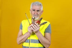 portrait of a mature worker wearing reflector vest isolated on yellow background photo