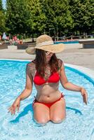 joven hermosa mujer con sombrero y rojo traje de baño relaja en el hidromasaje de nadando caca foto