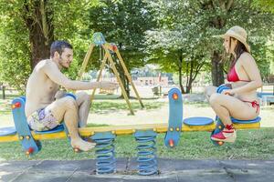 Couple of young adults have fun on a seesaw photo