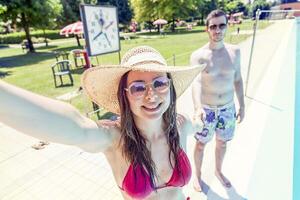 Young loving couple beside the pool takes a selfie photo