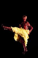 sensual woman dressed in a skeleton costume posing wearing a yellow skirt on a black background photo