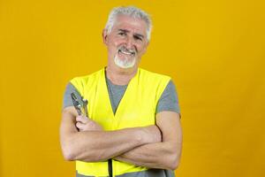 portrait of a mature worker wearing reflector vest isolated on yellow background photo