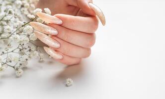 The nails are covered with pearl gel polish on white background photo