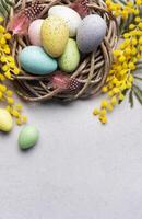 Colorful Easter Eggs Nestled in a Wicker Basket With Yellow Flowers on a Light Background photo