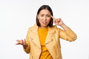 irritado asiático mujer rodar dedo cerca templo y curioso frustrado, regaño alguien estúpido o loco, en pie terminado blanco antecedentes foto