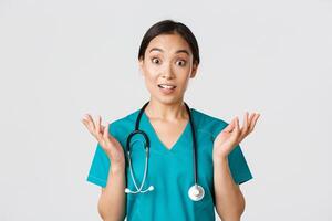 Healthcare workers, preventing virus, quarantine campaign concept. Close-up of surprised and amused, happy asian female nurse, physician hear great news, raise hands amazed and look camera photo