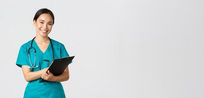 Healthcare workers, preventing virus, quarantine campaign concept. Cheerful friendly asian female physician, doctor with clipboard during daily checkup, standing white background photo