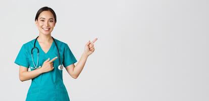 COVID-19, cuidado de la salud trabajadores, pandemia concepto. sonriente hermosa asiático hembra enfermero, interno señalando dedos Superior Derecha esquina, atractivo para chequeo, en línea clínica cita, blanco antecedentes foto