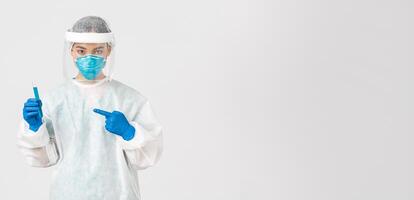 Covid-19, coronavirus disease, healthcare workers concept. Portrait of serious confident, asian female researcher, tech lab employee in personal protective equipment holding vaccine in test-tube photo