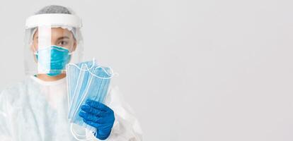 Covid-19, coronavirus disease, healthcare workers concept. Close-up of female asian doctor in personal protective equipment give patients medical masks to ensure safety, white background photo