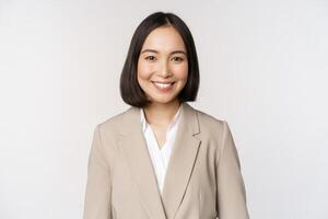 retrato de exitoso mujer de negocios en traje, sonriente y mirando me gusta profesional a cámara, blanco antecedentes foto