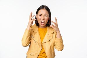 Asian angry woman arguing, shaking hands angry and screaming, shouting with frustrated face, standing over white background photo