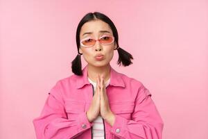 Please. Cute asian girl asking favour, begging, standing against studio background photo