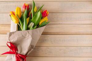 Bouquet of multicolored fresh tulips wrapped in eco-friendly craft paper. photo