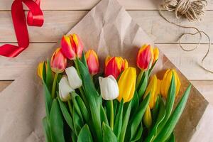 mujer florista corbatas rojo arco en grande ramo de flores de vistoso tulipanes Fresco primavera flores foto