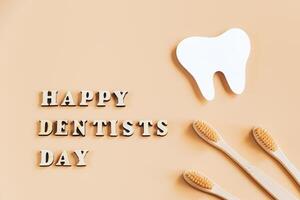 International Dentist Day. Eco-friendly wooden toothbrushes on beige background. Dental care concept. photo