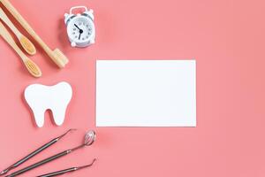 Dental care concept. Dental tools on pink background. Happy dentist day. Paper cut mockup of tooth. photo