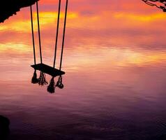 Wood swing beautiful sunset on the sea with pink sky background photo