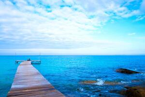 The wooden bridge stretches into the sea.With mountain clouds and sky. photo