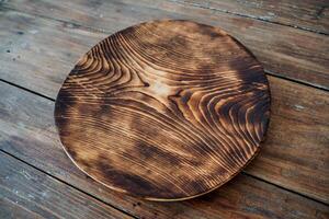 A round wooden plate stands on the table. For decoration, interior and food. On a blue natural background. photo