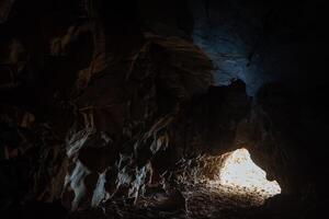 The light at the end of the tunnel. Exit from the cave. Dark passage in the dungeon. Speleotourism photo