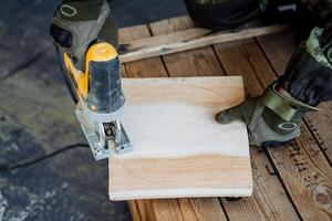 Creating a plate from natural material. Round wooden plate. A close shot of the hands of a master woodcarver. Carving a round plate from a square piece of wood. photo