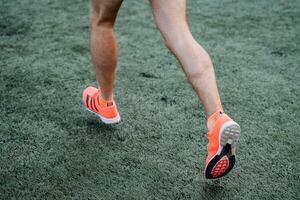 A close shot of the legs of a running man. Active recreation, sports and playing football. Bright sports uniform and shoes. Athletic physique and strong leg muscles. photo