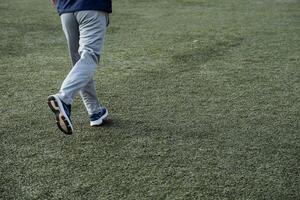 un hombre carreras a través de un verde fútbol americano campo en ropa de deporte. Deportes y jugando fútbol. activo capacitación, fortalecimiento de músculos y esqueleto. foto