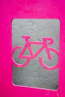 Bright pink sign with the image of a bicycle. Scenery on the street. Cycling. Active rest. photo