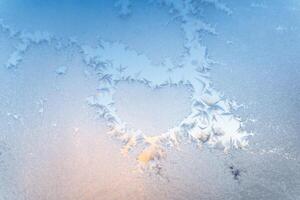 The texture of the glass covered with frost in winter in cold. Magical winter patterns. Natural phenomena. Frosty pattern in the shape of a heart photo