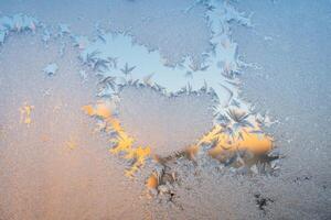 Magical winter patterns on the glass. Natural phenomena. Winter decorations, frozen water on the window. photo