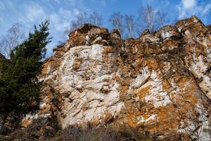 A shot from the bottom up of a steep steep rock covered with orange moss. An exciting sight. photo