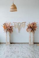 Interior shot. Bright room of the studio. There are two vases with leaves . The main element of the room vases, macrame and braided lampshade photo