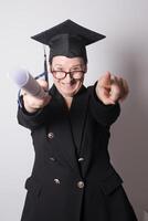 Mature woman with graduation cap very happy pointing at camera photo