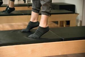 Close up of legs training on reformer bed photo