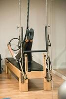 Unrecognizable woman training pilates with reformer bed photo